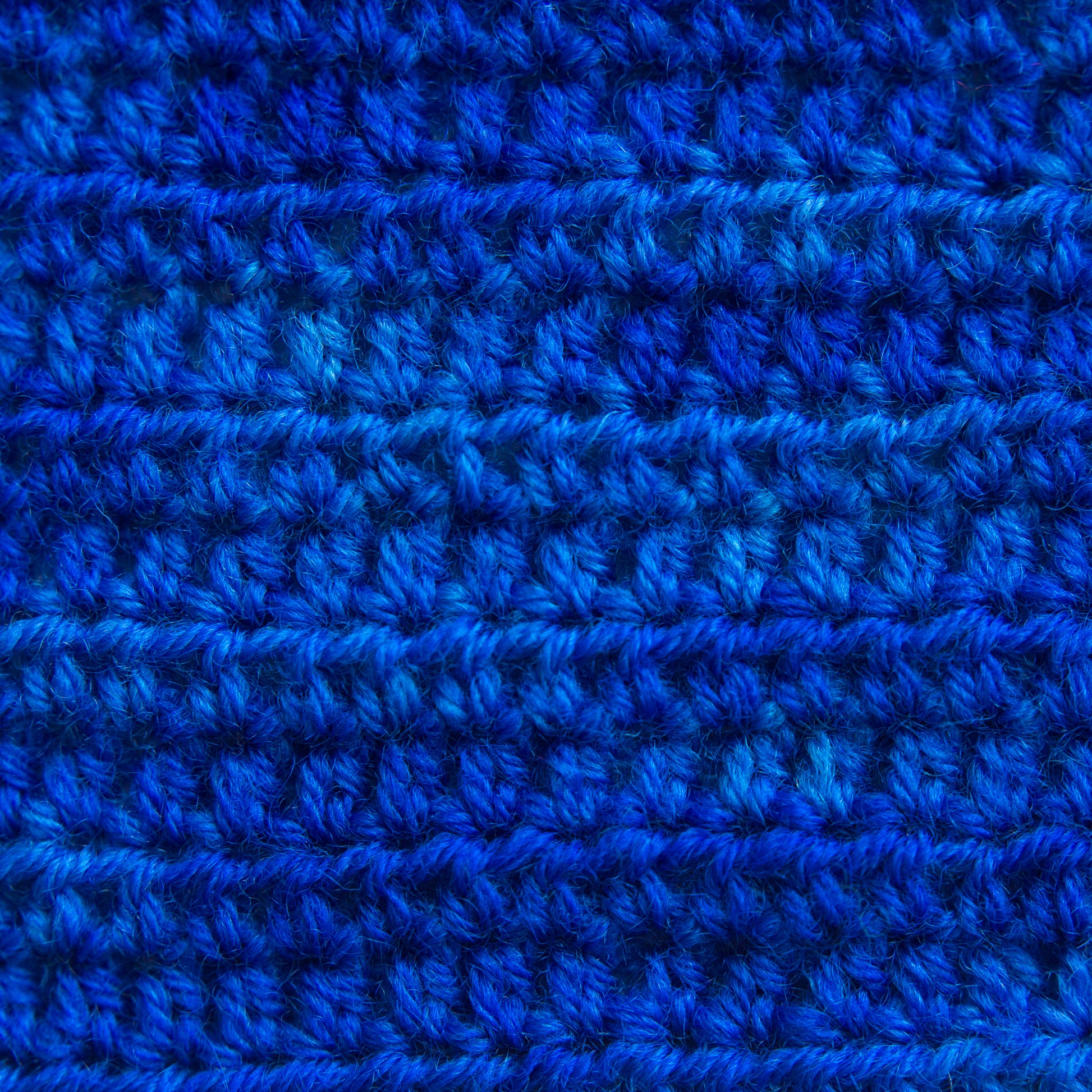 A close-up of a textured blue crocheted fabric.